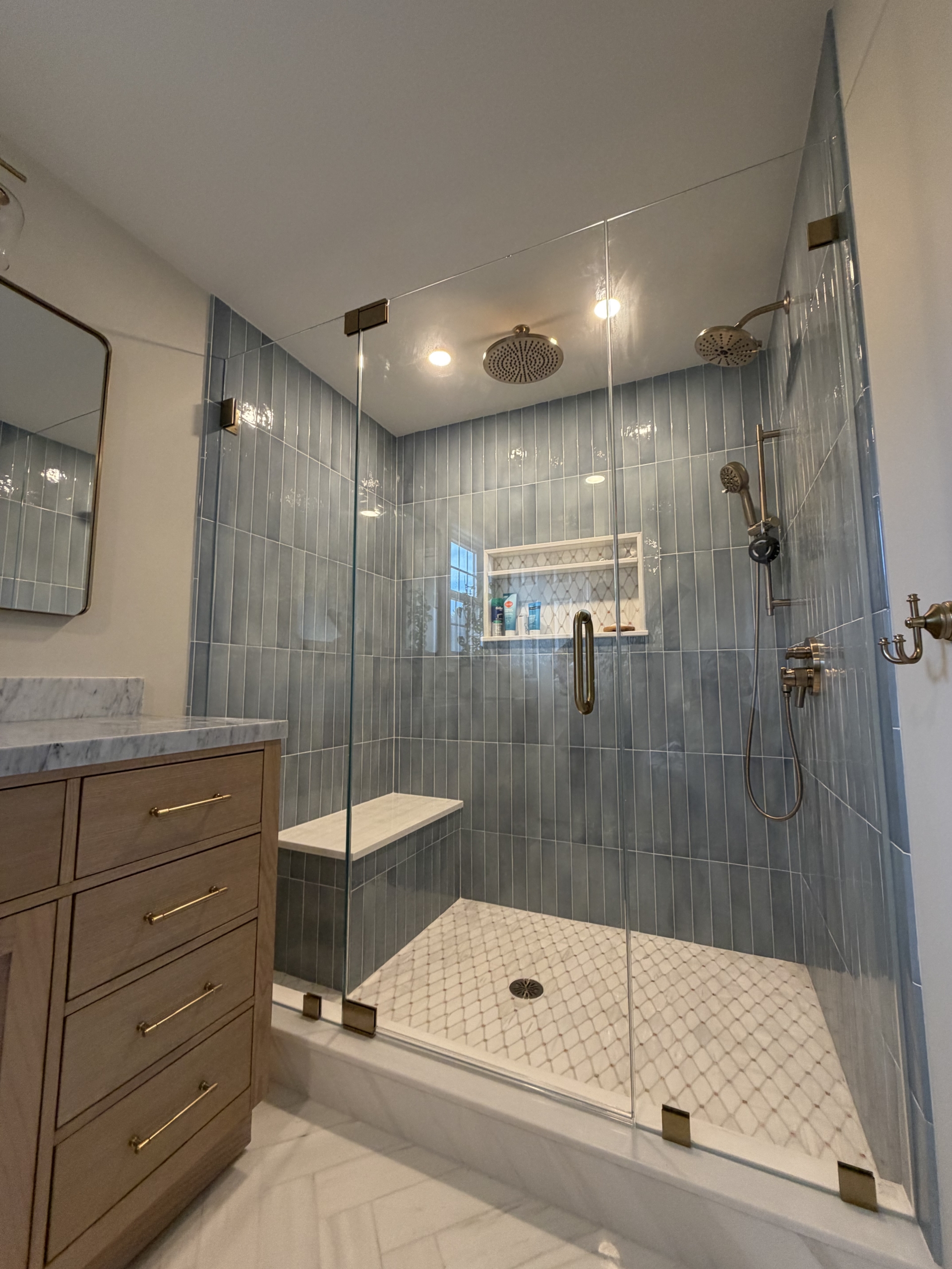 Pivot hinged frameless shower door installed in Greater Boston bathroom by LUXE Glass